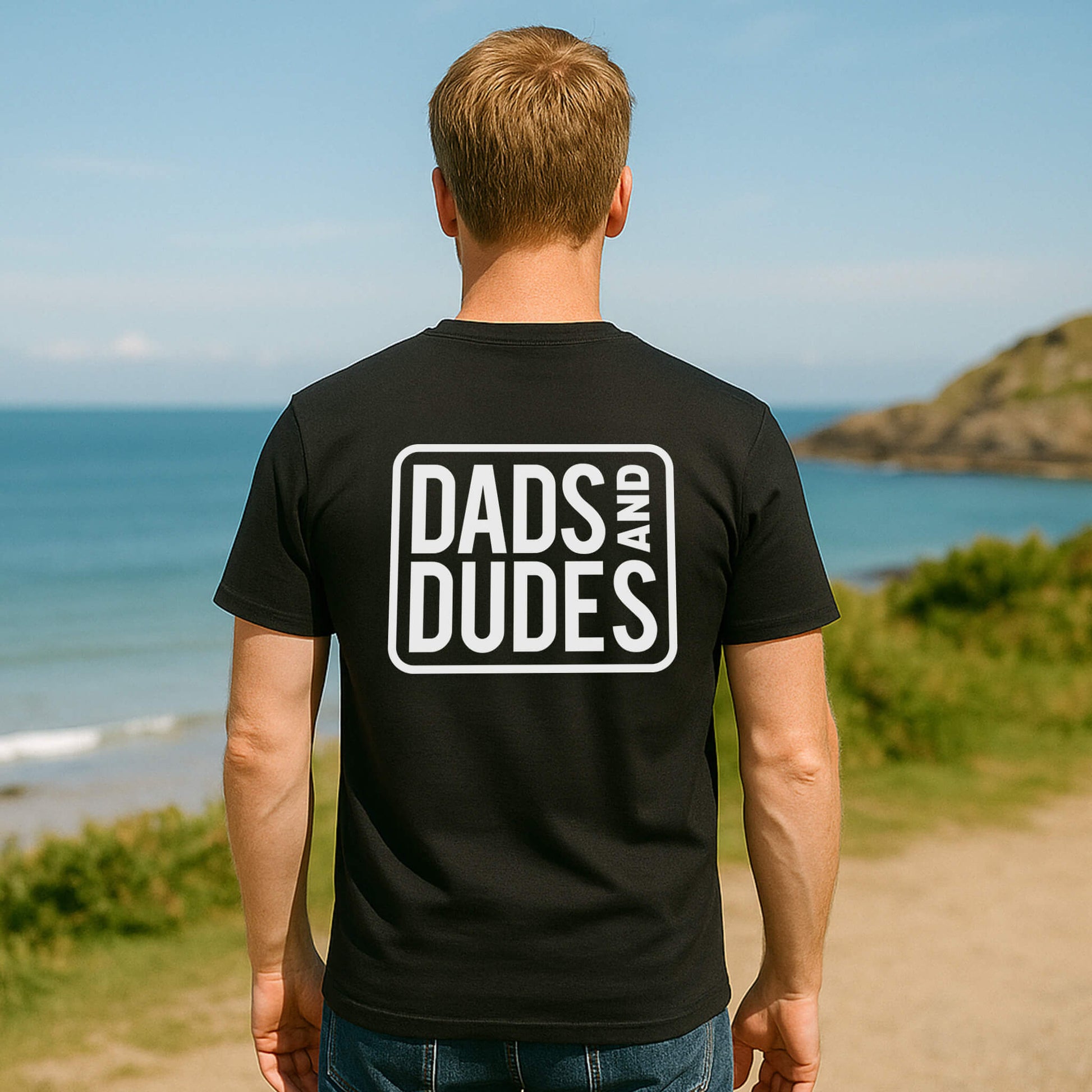 Back view of man wearing a Black Dads And Dudes Classic T-Shirt on the way to a beach workout.