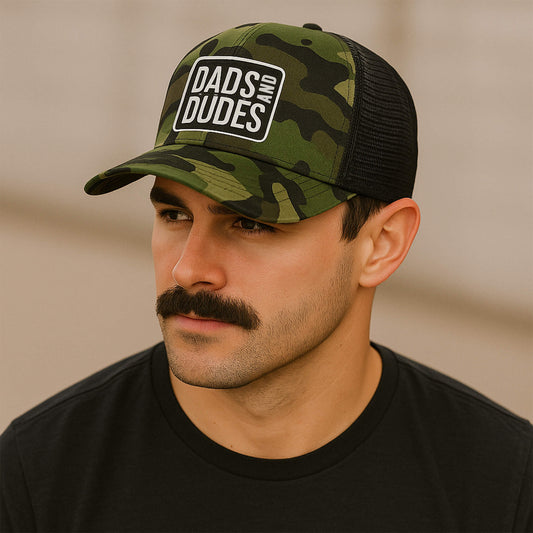 Man wearing Dads And Dudes Jungle Camo Embroidered Logo Trucker Cap.
