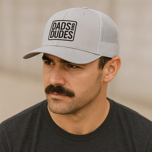 Man wearing Dads And Dudes Grey Embroidered Logo Trucker Cap.